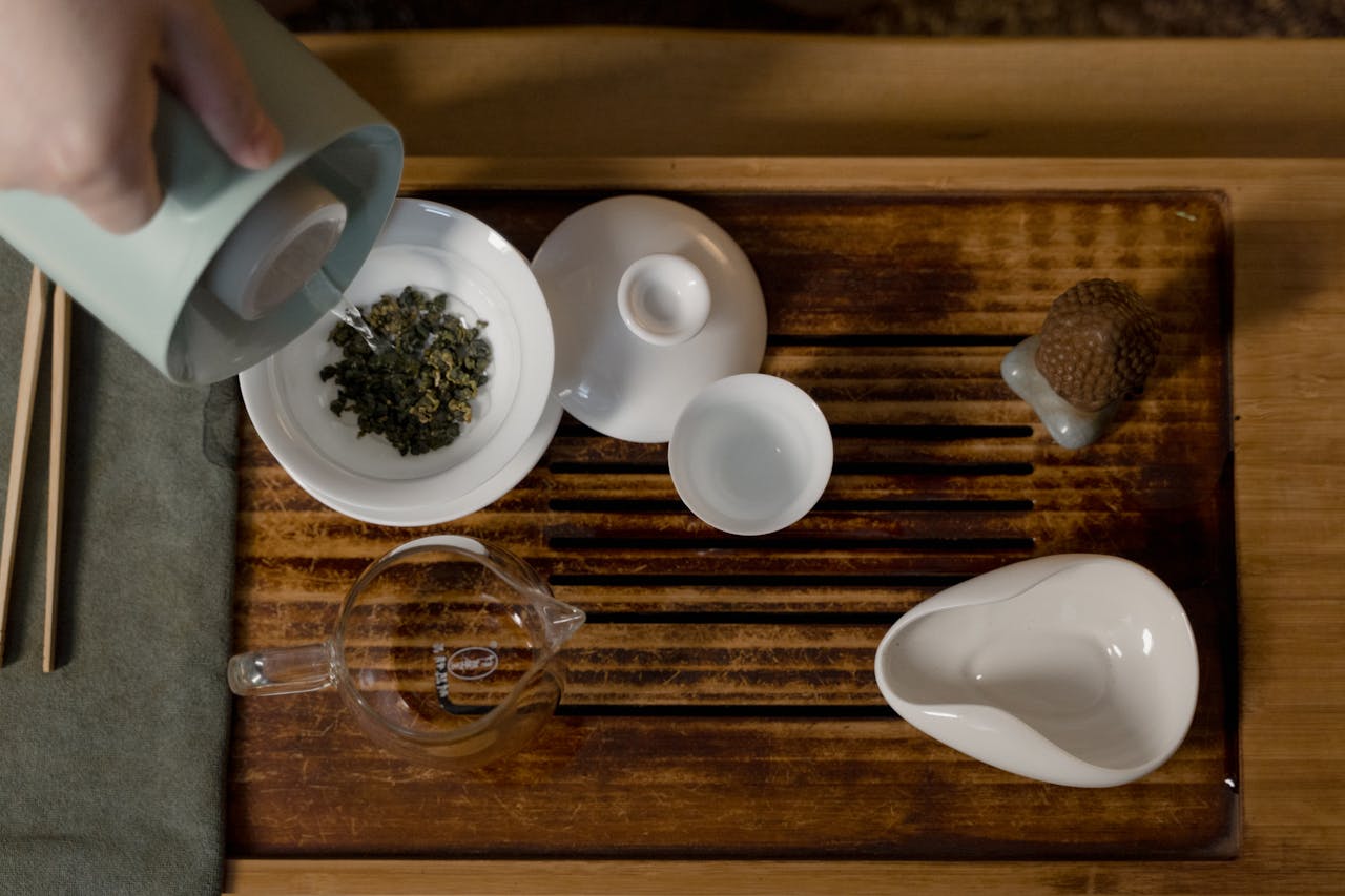Elegant setup of a traditional tea ceremony on a wooden board with porcelain ware.