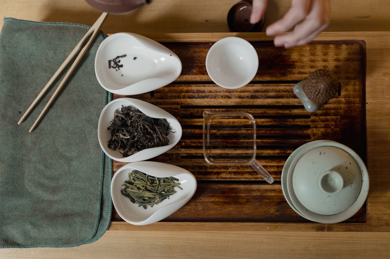 Elegant top view of a traditional tea set with various tea leaves and accessories.